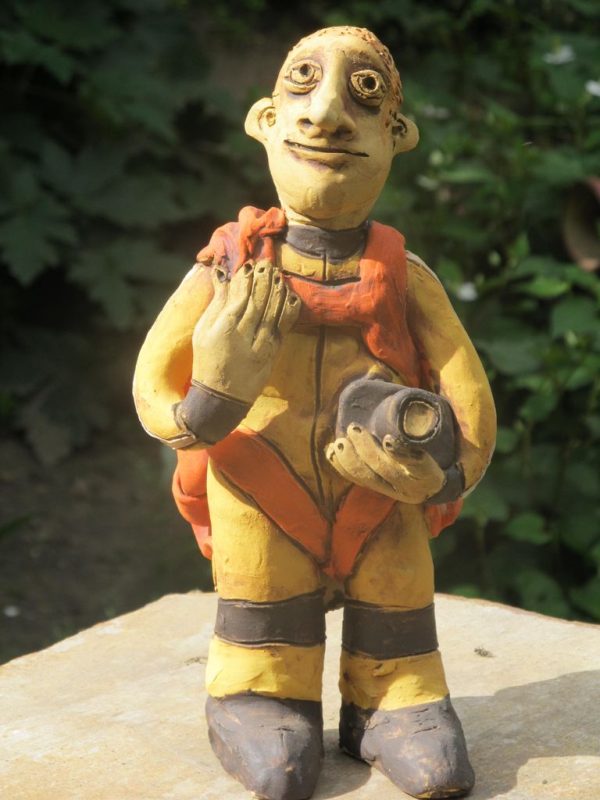 Kerámia ejtőernyős figura sárga ugróruhában.
